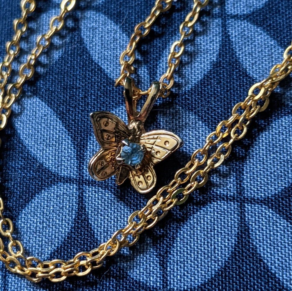 Gold butterfly shaped necklace with sapphire in the middle